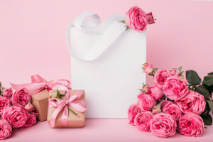 wedding welcome bag surrounded by pink roses and pink backdrop