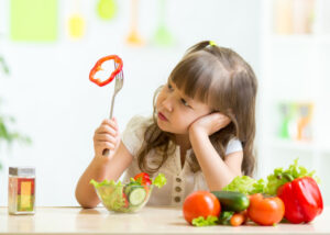young girl not wanting to eat salad