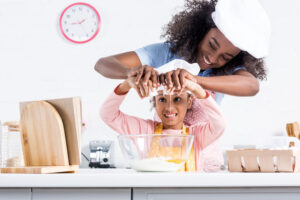 smiling mother and daughter baking in kitchen