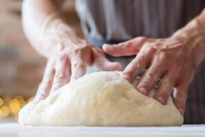 person kneading bread dough