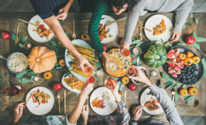 friends clinking glasses over friendsgiving meal