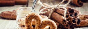 A pretzel topped with brown sugar and cinnamon. there is a bundle of cinnamon sticks tied behind the pretzel