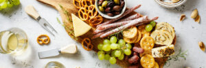 a charcuterie board with meats, olives, cheese, fruit, nuts, and pretzels.