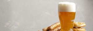 a glass of beer next to a stack of pretzels