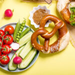 Pretzels and vegetables on yellow background, showing a balanced snack