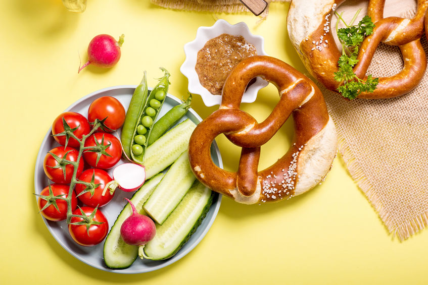 Pretzels and vegetables on yellow background, showing a balanced snack