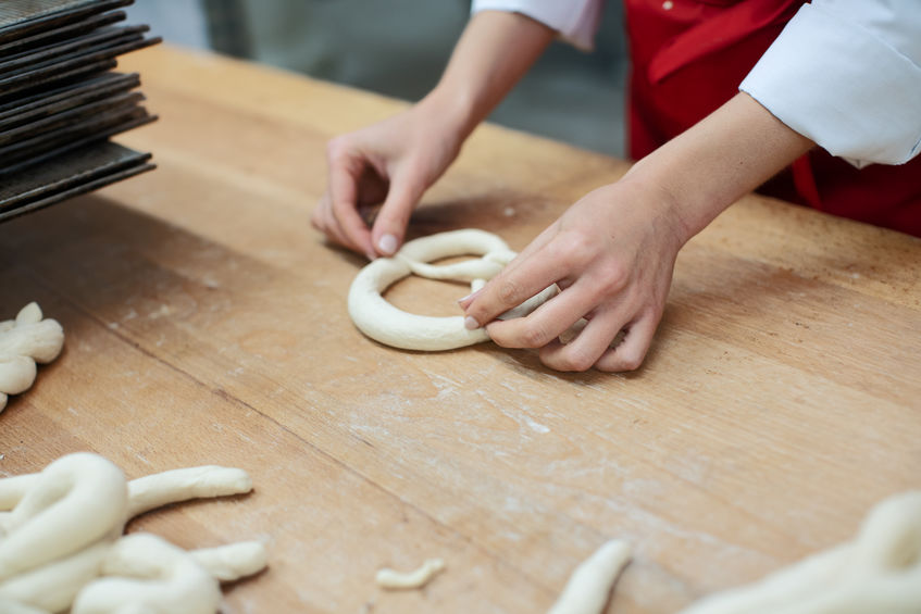 A baker making the twists while forming a pretzel