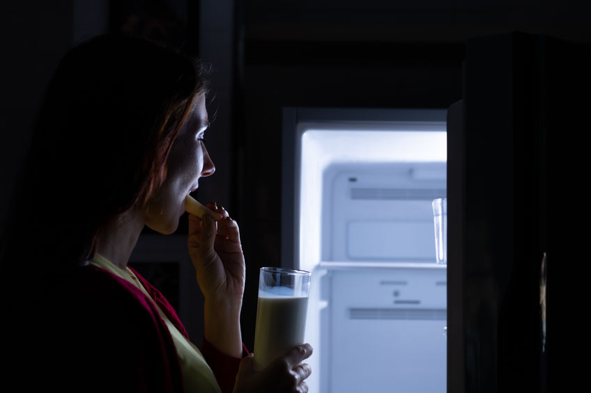 A woman enjoying a midnight snack while looking in the fridge