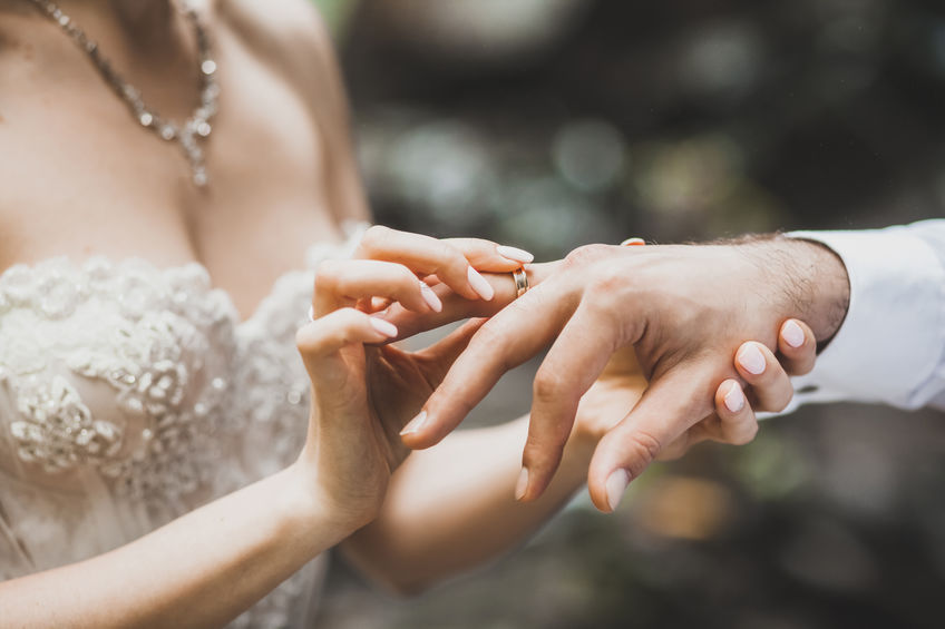 Bride putting ring on groom hand close-up