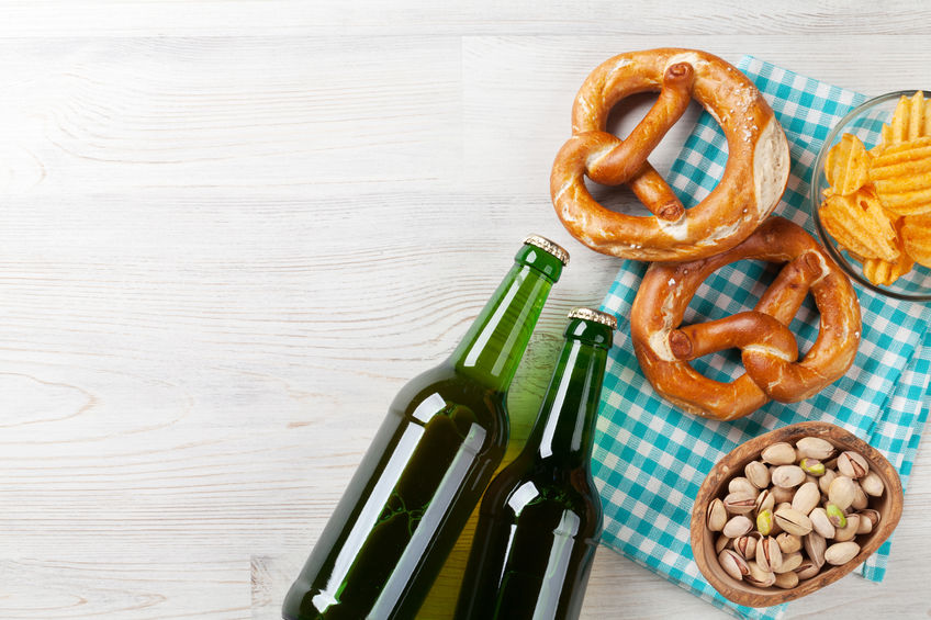 Lager beer and snacks on wooden table. Nuts, chips, pretzel. Top view with copy space