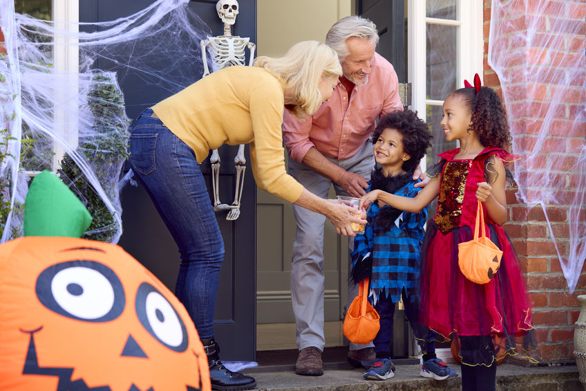 Grandchildren Dressing Up And Visiting Grandparent's House Trick Or Treating On Halloween